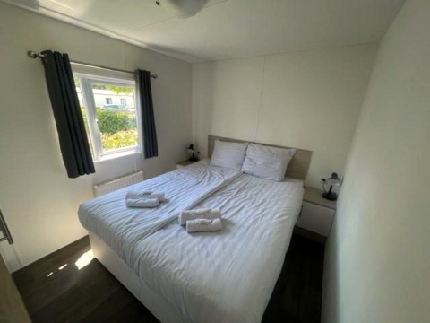 Lichte slaapkamer in de Berkel 6 lodge aan Zuiderzee, Nederland, met groot tweepersoonsbed en raam.