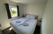 Chambre lumineuse de la Berkel 6 au Zuiderzee, Pays-Bas, avec lit double, fenêtre et décoration blanche.