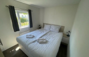 Bright bedroom in Berkel 6 lodge at Zuiderzee, Netherlands, featuring a double bed, window and white decor.