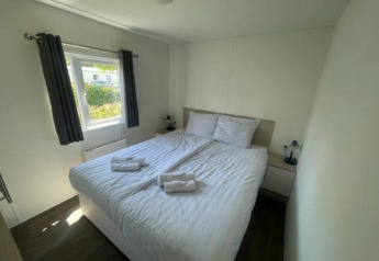 Helles Schlafzimmer in der Berkel 6 Lodge am Zuiderzee, Niederlande, mit Doppelbett und großem Fenster.
