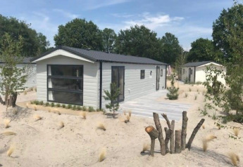 Moderne Berkel 6 Lodge bei Zuiderzee, Niederlande, umgeben von Sandlandschaft und Bäumen.