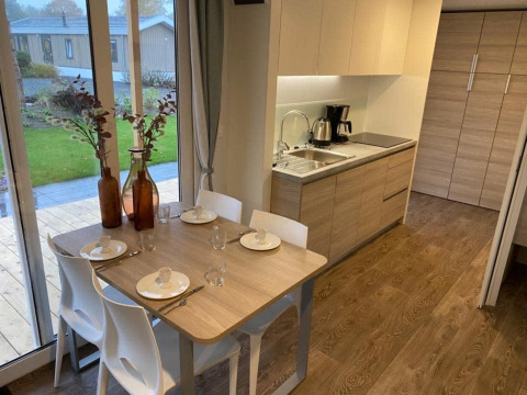 Moderne lodgekeuken en eettafel voor vier personen, grote ramen en uitzicht op groen bij Zuiderzee.