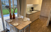 Moderne lodgekeuken met eettafel voor vier, grote ramen en tuinzicht in Zuiderzee, Nederland.