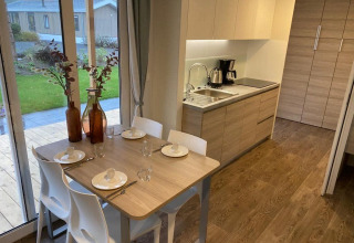 Cocina y comedor modernos en una cabaña, mesa para cuatro, ventanas grandes y vista verde en Zuiderzee.
