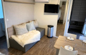 Salon moderne avec canapé, table à manger et télé à la lodge Cosy Unique 2+4 à Zuiderzee, Pays-Bas.