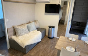 Moderne lodge zithoek met sofa, eettafel en TV bij Cosy Unique 2+4 in Zuiderzee, Nederland.