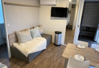 Moderne lodge zithoek met sofa, eettafel en TV bij Cosy Unique 2+4 in Zuiderzee, Nederland.