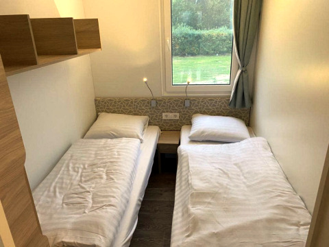 Twee eenpersoonsbedden in een knusse kamer van de Cosy Unique 2+4 lodge bij Zuiderzee, Nederland.