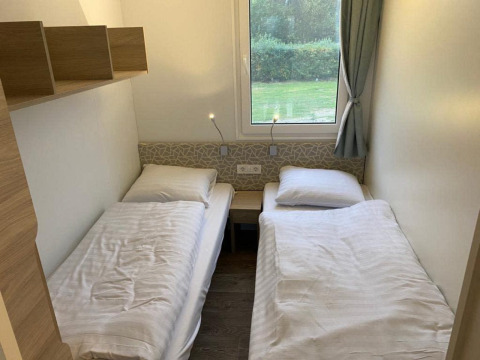 Twee eenpersoonsbedden in een gezellige kamer van de Cosy Unique 2+4 lodge aan Zuiderzee, Nederland.