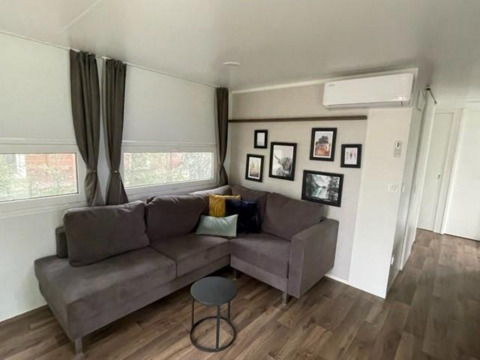 Woonkamer in Cosy Unique 4 lodge bij Zuiderzee, Nederland, met grijze bank en wanddecoratie.