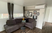 Living room in Cosy Unique 4 lodge at Zuiderzee, Netherlands, featuring a grey sofa and wall art.