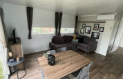 Lyst opholdsrum i Cosy Unique 4-lodge på Zuiderzee i Holland med sofa, TV og spisebord.