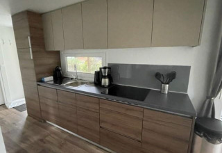 Modern kitchen area in Cosy Unique 4 lodge at Zuiderzee, Netherlands, with wooden finish and window.