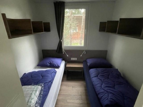 Twee eenpersoonsbedden met blauwe dekbedden in een kleine kamer bij Cosy Unique 4, Zuiderzee, Nederland.