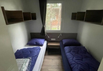 Twee eenpersoonsbedden met blauwe dekens in een kleine kamer van Cosy Unique 4, Zuiderzee, Nederland.