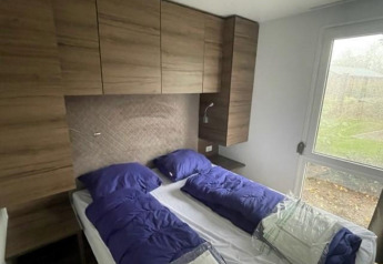 Slaapkamer in Cosy Unique 4 lodge aan de Zuiderzee in Nederland, met twee bedden, houten kasten, raam.