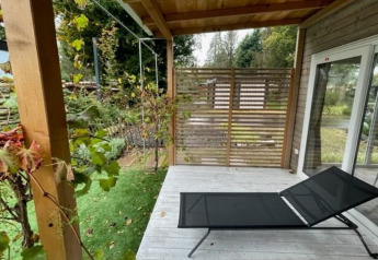 Veranda mit Liegestuhl bei Cosy Unique 4 im Zuiderzee, Niederlande, mit Blick auf Garten.