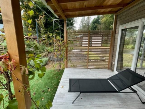 Outdoor veranda at Cosy Unique 4, Zuiderzee, Netherlands, featuring a sun lounger and green garden.