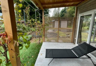 Outdoor veranda at Cosy Unique 4, Zuiderzee, Netherlands, featuring a sun lounger and green garden.