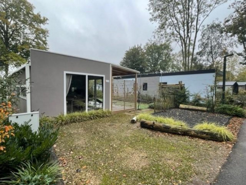 Buitenaanzicht van Cosy Unique 4 lodge bij Zuiderzee in Nederland met tuin en omringende bomen.