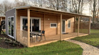 Foto de Cottage 4, una casa de madera moderna con porche cubierto y muebles de exterior en un entorno verde.