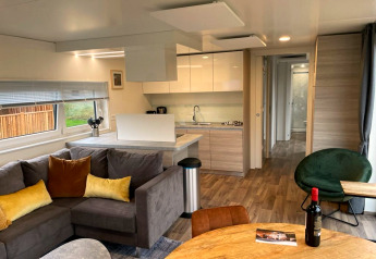 Soggiorno e cucina moderni nel Cottage 4 a Zuiderzee, Paesi Bassi, con arredi eleganti in legno.