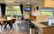 Sala moderna en Cottage 4 de Zuiderzee, Países Bajos, con comedor, sofá y vista al jardín exterior.