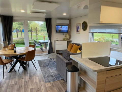 Sala moderna en Cottage 4 de Zuiderzee, Países Bajos, con comedor, sofá y vista al jardín exterior.