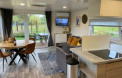 Sala moderna en Cottage 4 de Zuiderzee, Países Bajos, con comedor, sofá y vista al jardín exterior.