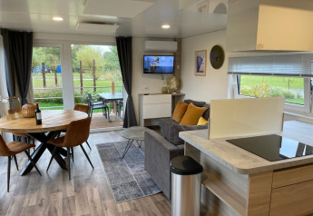 Moderne leefruimte in Cottage 4 aan Zuiderzee, Nederland, met eettafel, sofa en zicht op de tuin.