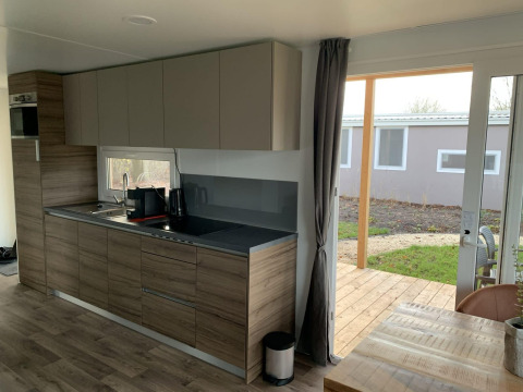 Moderne køkkenindretning i et sommerhus med træfinish og udsigt til udendørs terrasse ved Zuiderzee.
