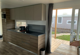 Moderne køkkenindretning i et sommerhus med træfinish og udsigt til udendørs terrasse ved Zuiderzee.