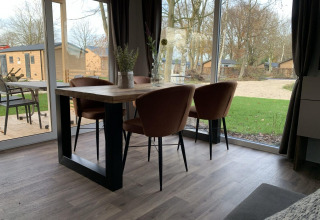 Mesa de comedor con cuatro sillas en una cabaña con vista al césped y árboles en Zuiderzee, Países Bajos.