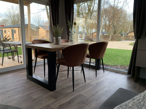 Spisebord med fire stole i en lodge med udsigt til grøn græsplæne og træer på Zuiderzee, Nederlandene.