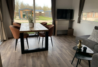 Sala moderna en Cottage 4 en Zuiderzee, Países Bajos, con mesa de comedor, sillas, televisor y amplias ventanas.