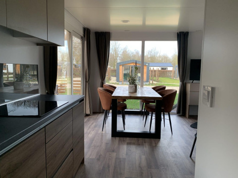 Comedor y cocina modernos en una cabaña de Zuiderzee, Países Bajos, con grandes ventanales y vista al jardín.