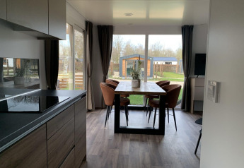 Moderne eetkamer en keuken in een lodge aan het Zuiderzee, Nederland, met zicht op de tuin.