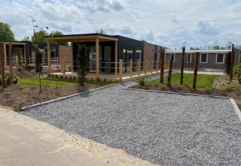 Moderne lodge Cottage 4 aan Zuiderzee in Nederland met kiezelpad, tuin en ruime houten terrasoverkapping.