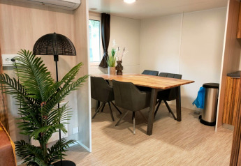 Comedor en Cottage 5 en Zuiderzee, Países Bajos, con mesa de madera, plantas y decoración moderna.