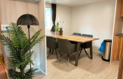 Comedor en Cottage 5 en Zuiderzee, Países Bajos, con mesa de madera, plantas y decoración moderna.