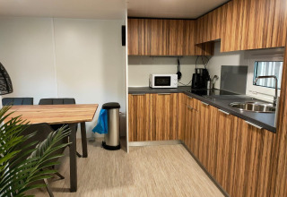 Moderne køkken og spisestue i Cottage 5 på Zuiderzee med træskabe, spisebord og hvidevarer.