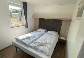 Dormitorio luminoso con dos camas individuales y ventana en Cottage 5, Zuiderzee, Países Bajos, estilo moderno.