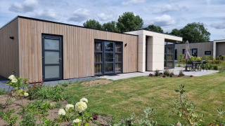 Lodge Cube Maximaal 4 con rivestimento in legno moderno, ampie finestre e giardino curato fuori.