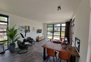 Modern living room with large windows, dining area, and cozy seating in Cube Maximaal 4, Zuiderzee, Netherlands.