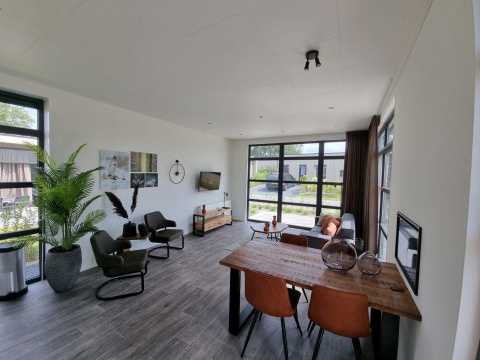 Modern living room with large windows, dining area, and cozy seating in Cube Maximaal 4, Zuiderzee, Netherlands.
