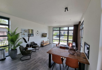 Moderne woonkamer met grote ramen, eetruimte en gezellige zitplaatsen in Cube Maximaal 4, Zuiderzee, Nederland.