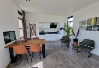 Moderne leefruimte van Cube Maximaal 4 lodge aan Zuiderzee in Nederland, met keuken en eettafel.