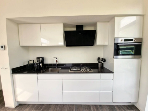 Modern kitchen area in Cube Maximaal 4 lodge at Zuiderzee, Netherlands, with white cabinets and appliances.