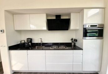 Moderna area cucina al Cube Maximaal 4 lodge a Zuiderzee, Paesi Bassi, con armadi e elettrodomestici bianchi.