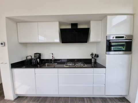 Moderne keuken in Cube Maximaal 4 lodge bij Zuiderzee, Nederland, met witte kasten en apparatuur.